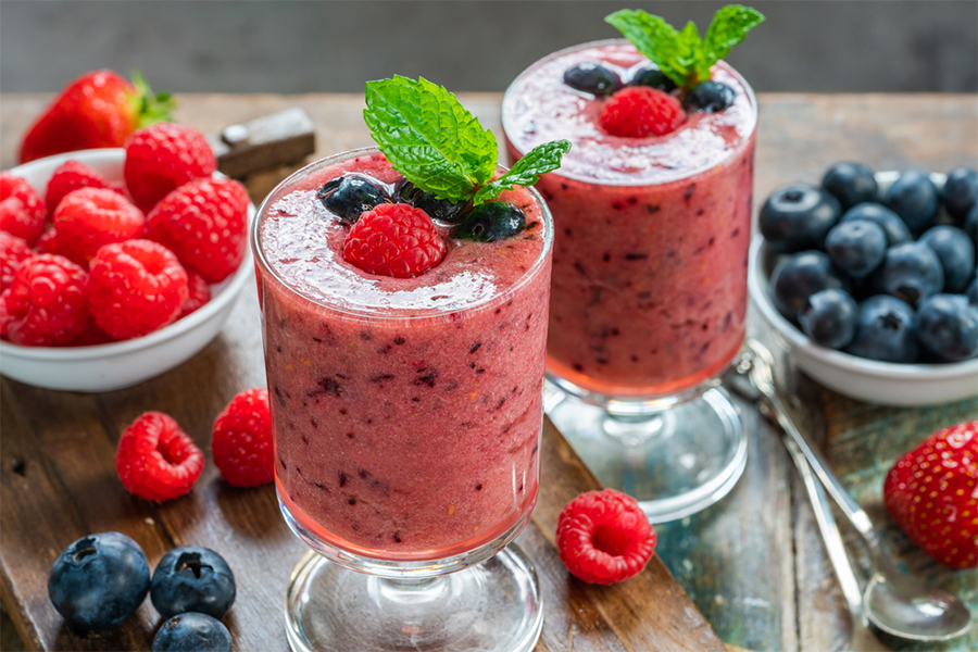 2 glasses of Berry Antioxidant Smoothie with raspberries and blueberries aroud them
