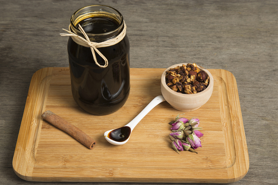 Jar of molasses on a cutting board with a bowl of granola