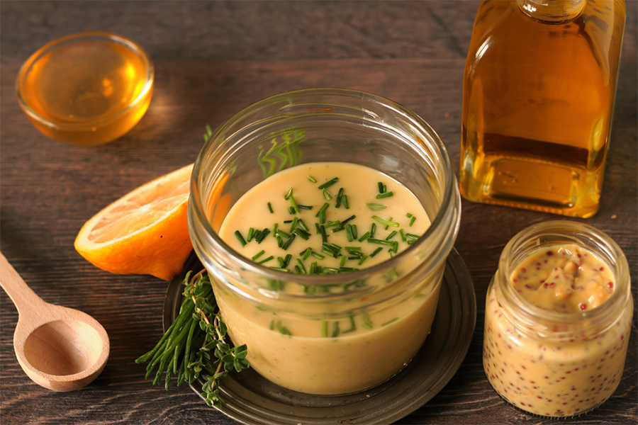 Small jar with Mustard Chive Vinaigrette, and ingredients around it