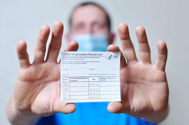 Man holds out COVID-19 vaccination record card