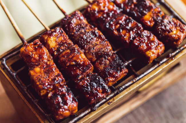 Skewers of BBQ tempeh on a grill