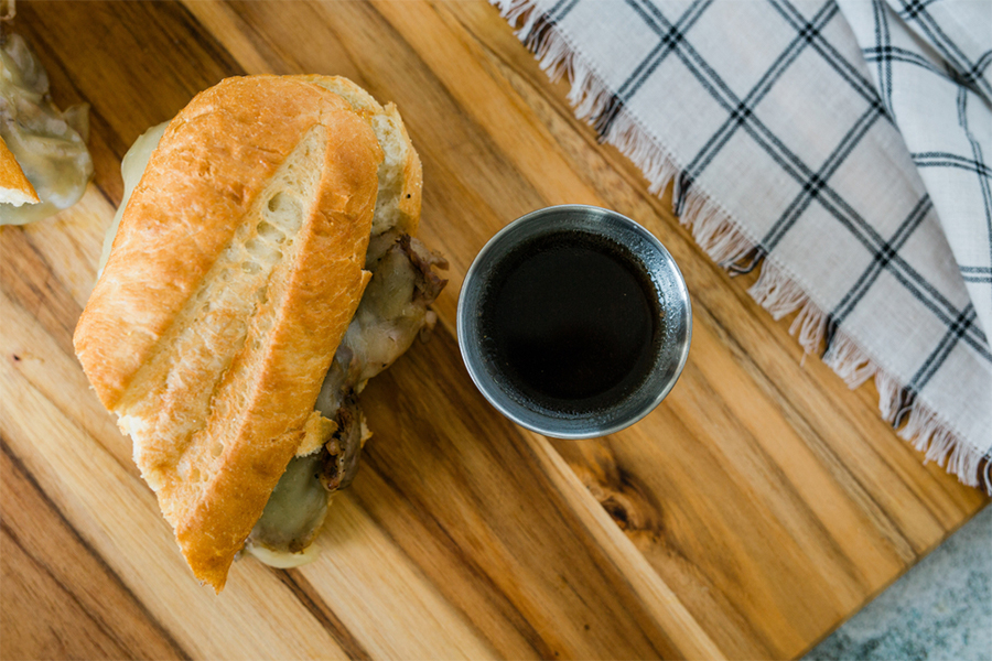 Portobello Mushroom French Dip Sandwich next to a cup of dipping sauce