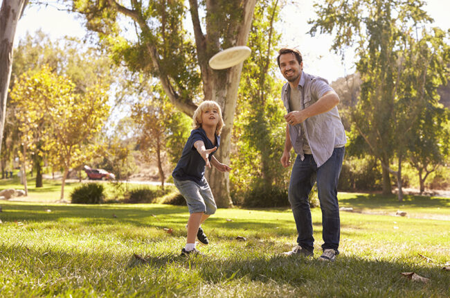 Father and son playing frisbee in the park