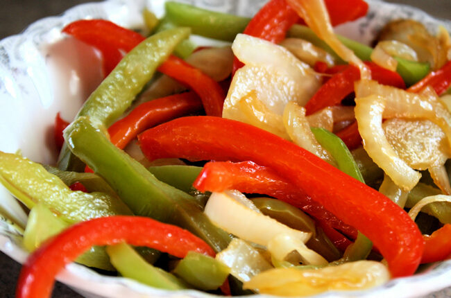 Close up of cooked red and green bell peppers and onions