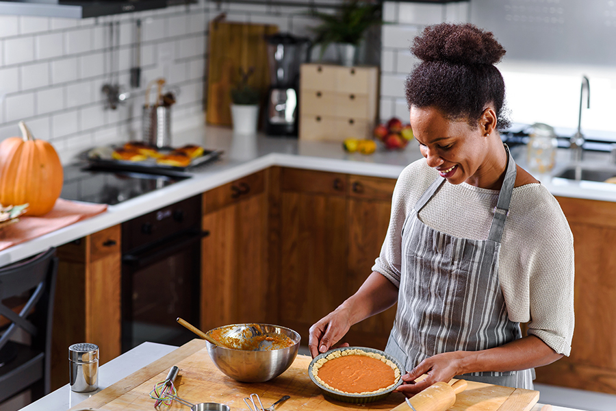 African american woman preparing pumpkin pie for holidays