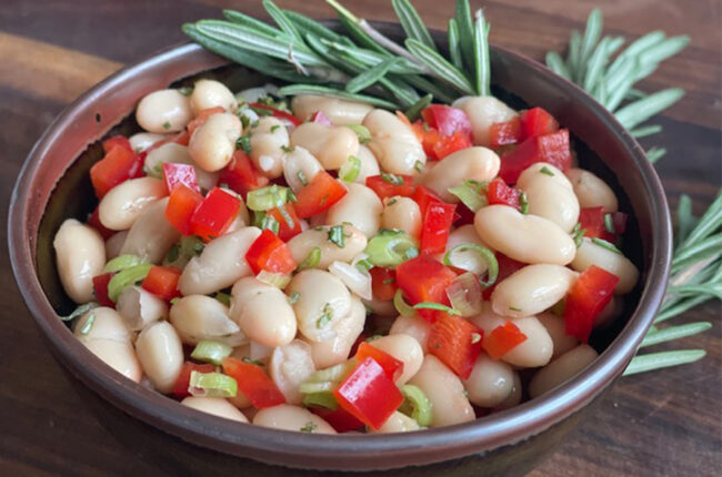 Bowl of white beans, tomatoes and rosemary sprigs