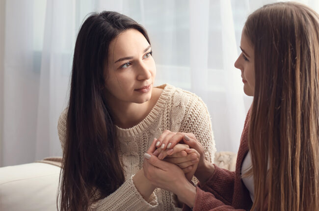 Woman holding her friend's hands in comfort, having serious conversation