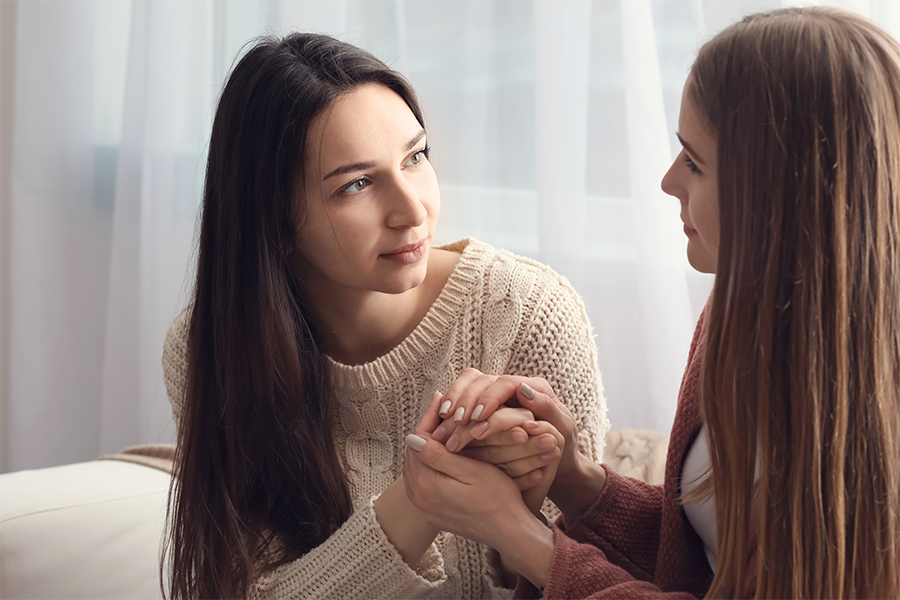 Woman holding her friend's hands in comfort, having serious conversation