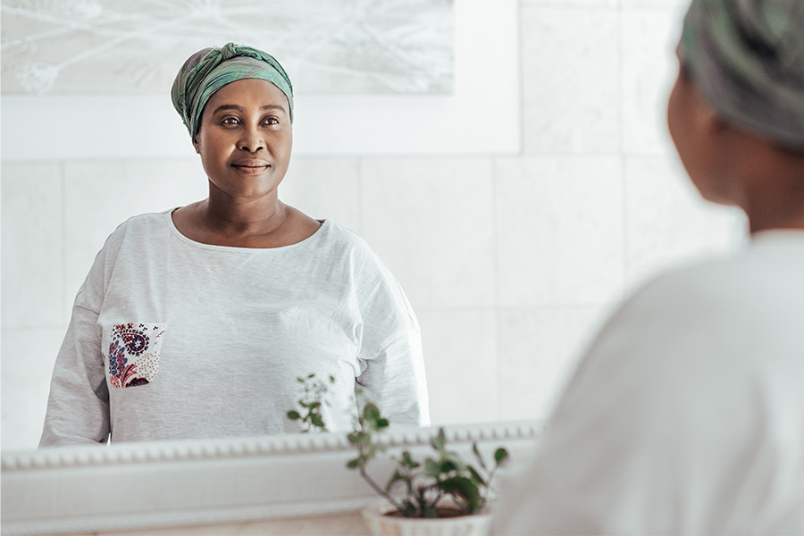 African woman wearing a headscarf looking in the mirror