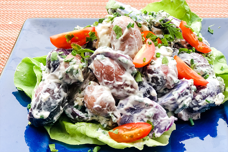 Salad with blue potatoes, tomatoes and mayonaise on a lettuce leaf