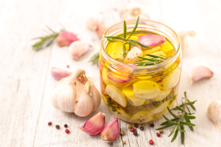 Small jar of olive oil infused with garlic cloves and rosemary