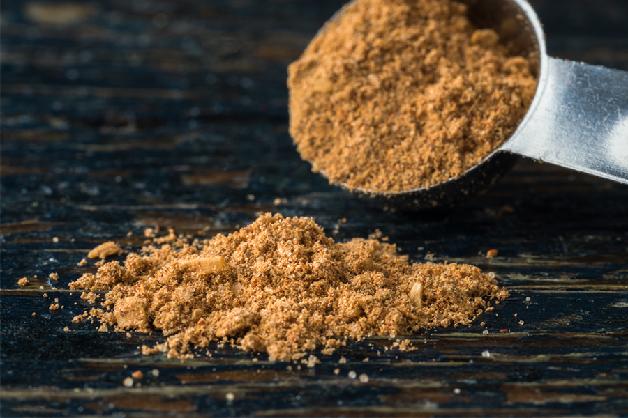 Close up of tablespoon of taco seasoning being sprinkled on a table