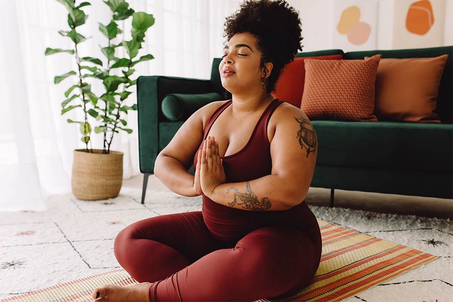 Plus size woman practicing yoga meditation at home