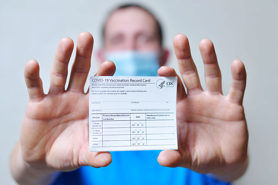 Man holds out COVID-19 vaccination record card