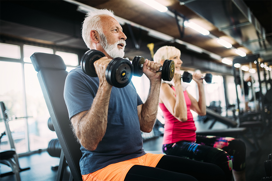 Happy senior couple doing exercises in gym to stay fit
