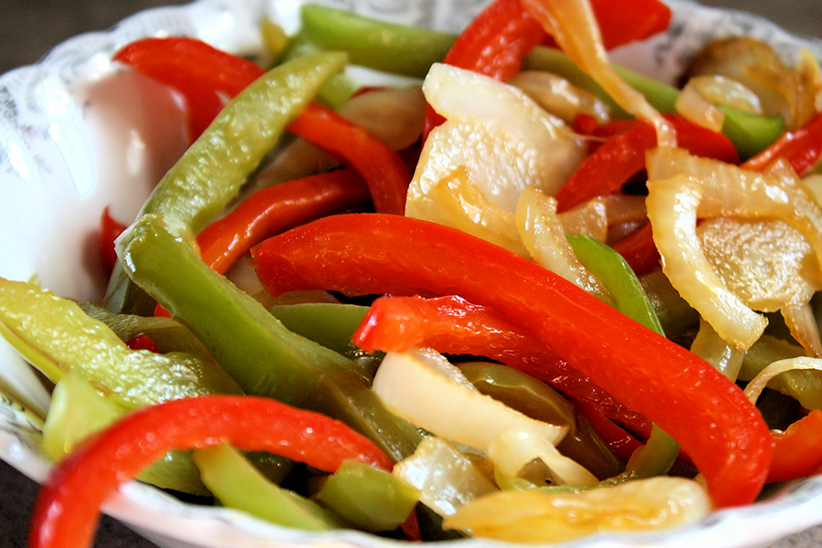 Close up of cooked red and green bell peppers and onions