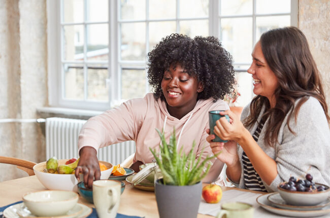 2 women eating fruit at dining table and chatting