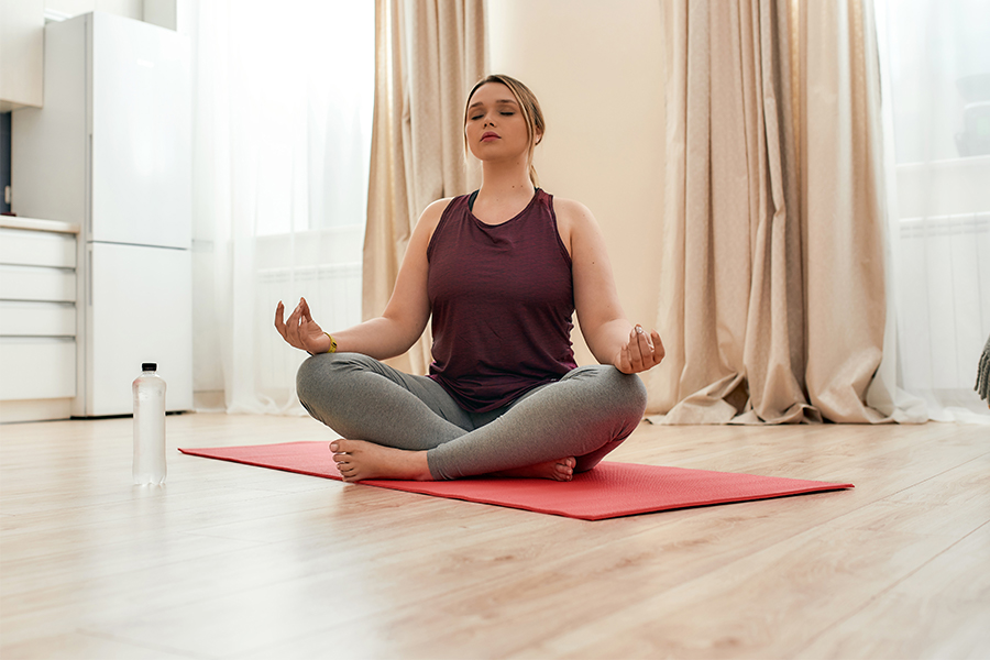 Woman sitting on yoga mat, cross legged, meditating