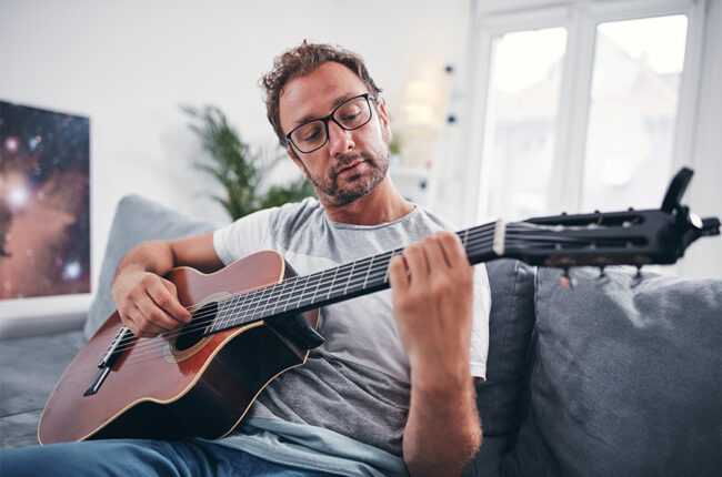 Man sitting on couch playing guitar