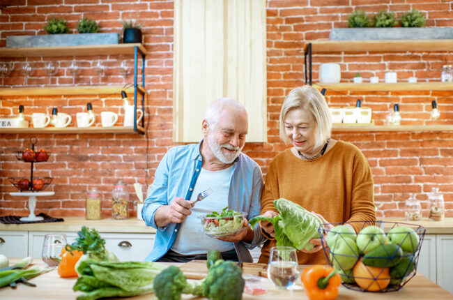 Eldery couple making healthy salad in their kitchen