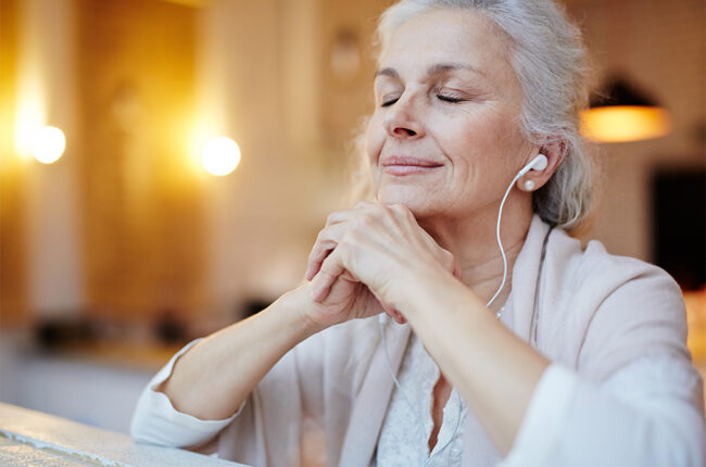 Older woman listening to music on earphones, eyes closed