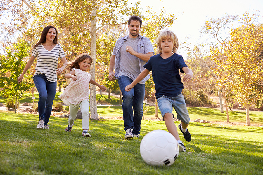 Family playing soccer in the park
