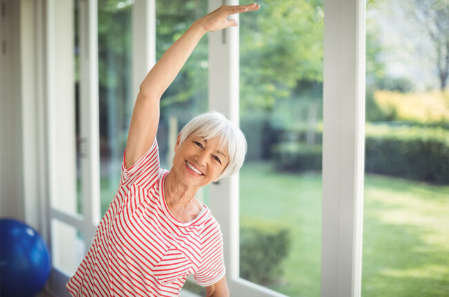 Older woman leaning with arm overhear, stretching