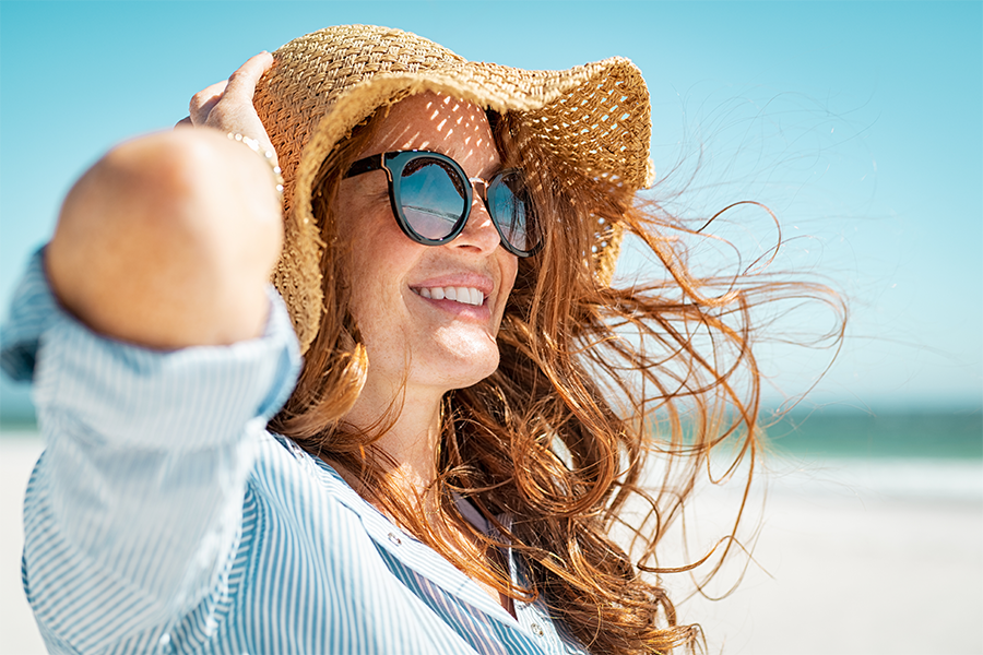 Redhead woman on the beach with sunglasses and a sunhat