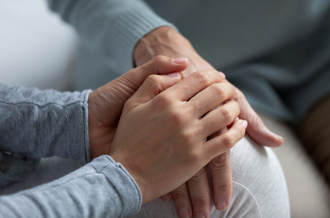 close up of hands holding another person's hands in comfort