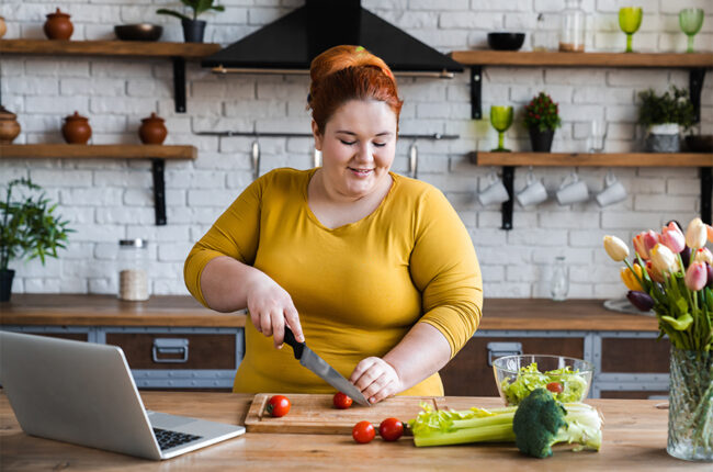 Plus size woman in kitchen cutting tomatoes