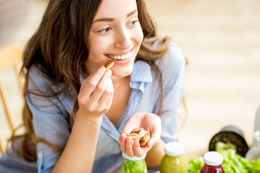 Closeup view from above of a woman eating brasil nuts with healthy food on the background