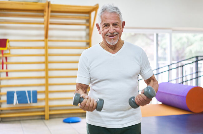 Happy elderly man exercising with dumbbells