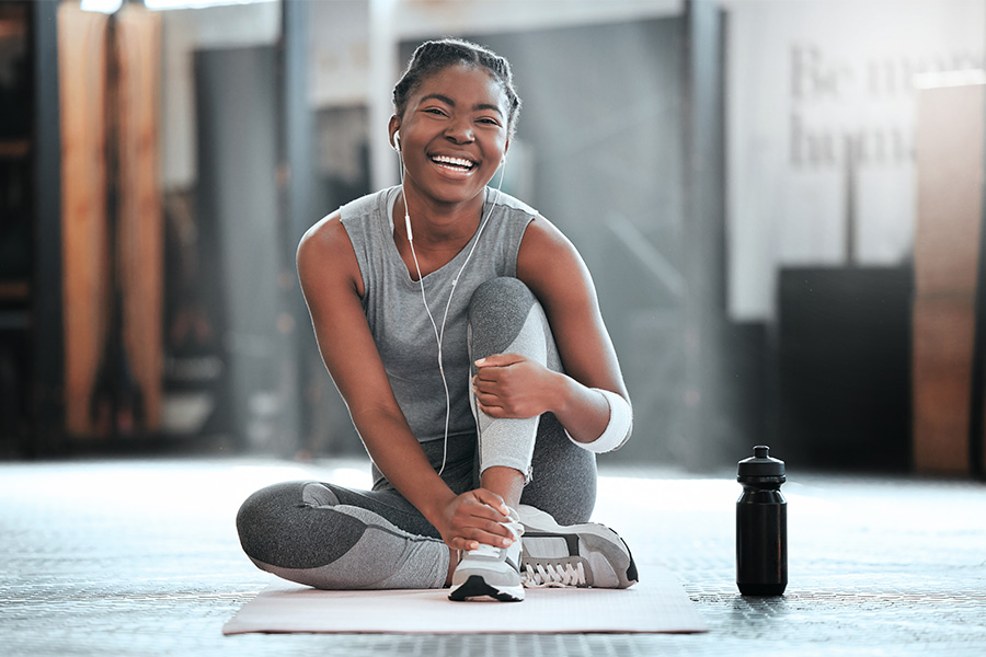 Young black woman sitting on floor in workout clothes smiling