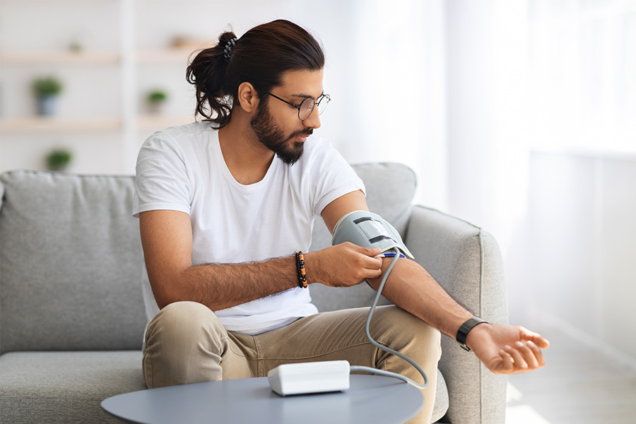 Young indian man checking blood pressure at home