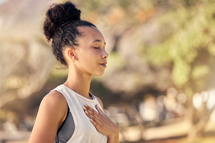 Black woman, breath and hand on chest, for meditation and wellness being peaceful to relax. Bokeh, African American female and lady outdoor, in nature and being calm for breathing exercise and health