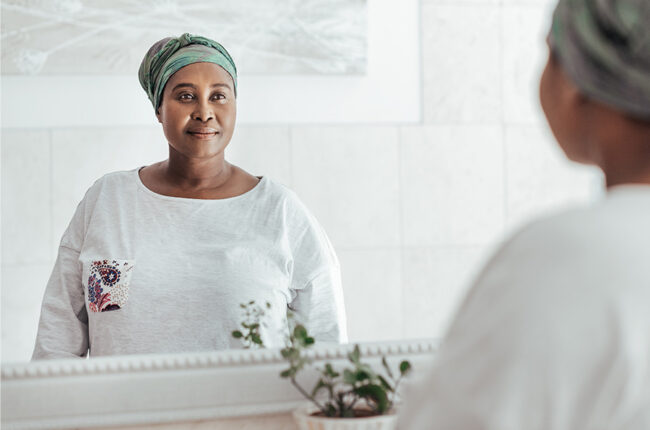 African woman wearing a headscarf looking in the mirror