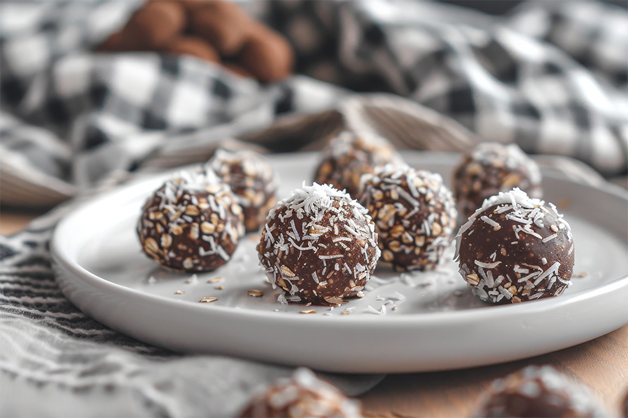 Vegan chocolate truffles made with dates coconut flakes and oats served on a white plate